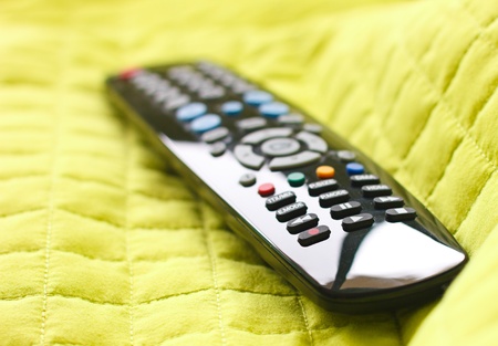 Black remote control on green blanket.Focus in record button.