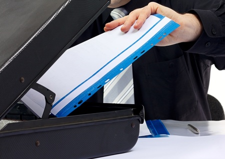 Close-up of business man hand holding some blank documents.Open suitcase.