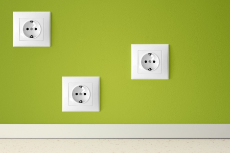 Green wall with three european electric outletsの写真素材