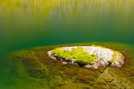 Small island in very clean water of a glacier lake.Copy space for text.Little waves moving in slow motion.の写真素材