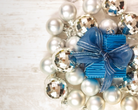Top view of blue gift box surrounded by silver baubles against wooden white table Space for text on the left の写真素材