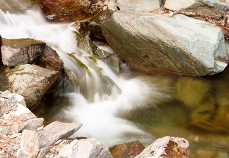 Long exposure photo of beautiful cascade through mountain rocksの写真素材