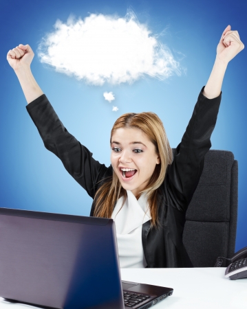 Successful business woman sitting at her desk in front of laptop. White cloud for custom text.の写真素材