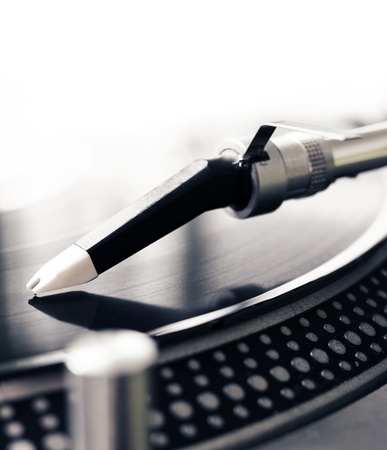 Low angle view of old fashioned turntable playing a track from black vinyl.Color cross processed.の写真素材
