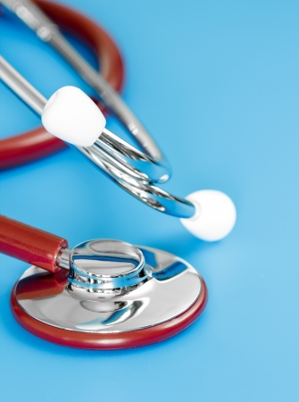 Closeup of red stethoscope on blue background.の写真素材