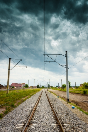 View of straight railroad with dark cloudy sky. Dramatic look while daytimeの写真素材