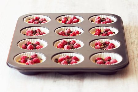 Low angle view of metallic black tray filled with unripe muffins ready to be baked. Muffins are very...