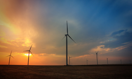 Rotating wind turbines at sunset against beautiful sky
