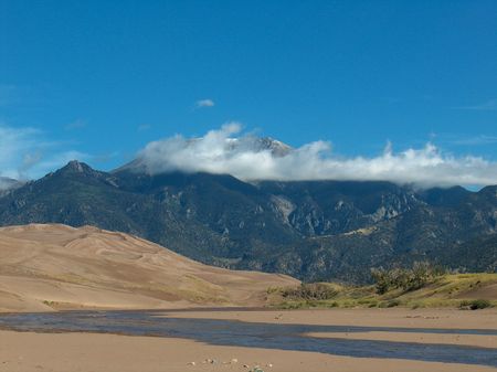 mountain with sand dunes and river under blue skies and cloudsの写真素材