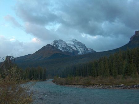 Snowy mountain top with blue stream in foregroundの写真素材