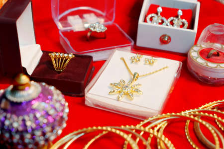 Indian wedding Jewellery set of earrings, ring, necklace decorated in a wedding function, isolated on red shiny cloth. Engagement rings and jewellery set on a red velvet cloth background.の写真素材