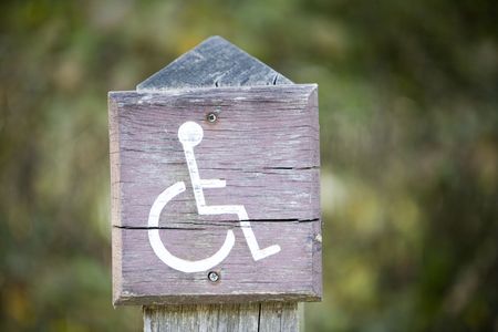 weathered looking disable parking place sign on a post in a carparkの写真素材