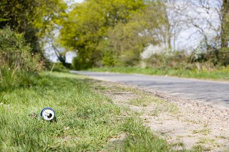 can of drink by a curved road down a country lane lined with green trees on both sidesの写真素材