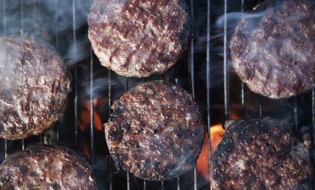 beef burgers cooking on a BBQの写真素材