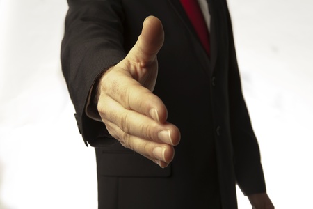 man in business suit and red tie about to shake your hand