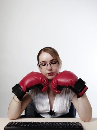woman at her desk wearing boxing gloves trying to workの写真素材