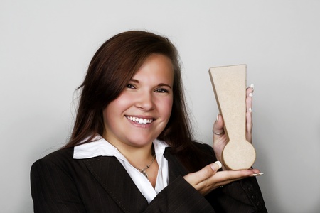 woman in a suit holding up a exclamation mark in her handsの写真素材