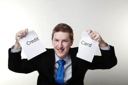 man in a suit sat at a desk holding up a ripped up  piece of paper in two hands with the words debit card printed on it and looking happyの写真素材