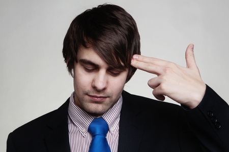 businessman shooting his own head with his fingersの写真素材