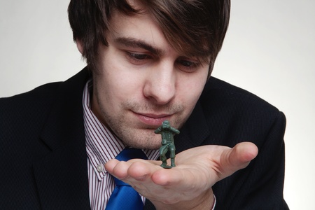 close up detail shot of business man playing with toy soldiers in his hand