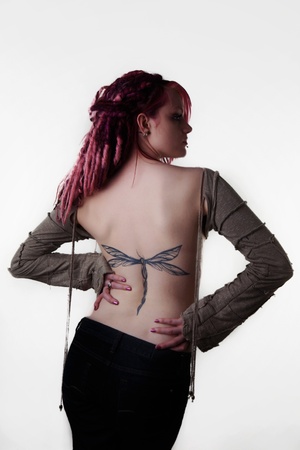 woman with dread lock hair showing off her large back tattoo of a dragonflyの写真素材