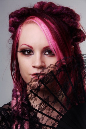 woman with dread lock hair holding a fan up to her faceの写真素材