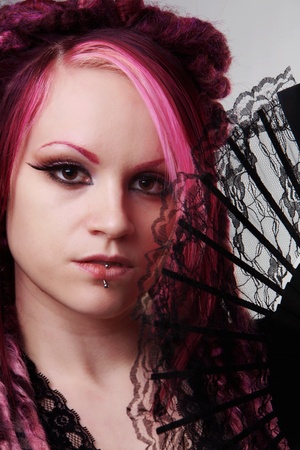woman with dread lock hair holding a fan up to her faceの写真素材