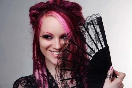 woman with dread lock hair holding a fan up to her faceの写真素材