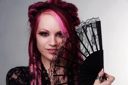 woman with dread lock hair holding a fan up to her faceの写真素材