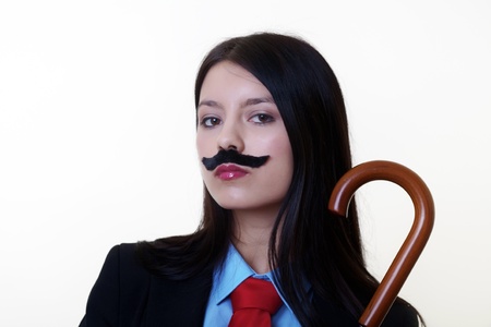 portrait of a young woman dressed up in a man's suit and tie wearing a fake mustache holding a umbrellaの写真素材