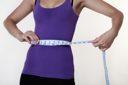 Closeup of tape measure around woman waist の写真素材