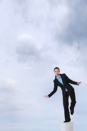 business woman standing on a very large stack of paper work, going high up into a sky  の写真素材