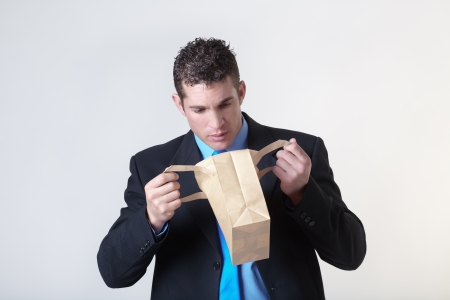 businessman looking into a paper bag to see what he can find