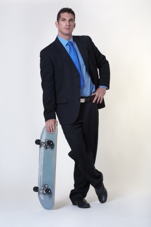 business man standing holding a skateboardの写真素材