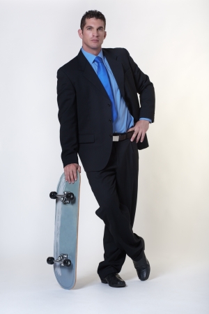 business man standing holding a skateboardの写真素材