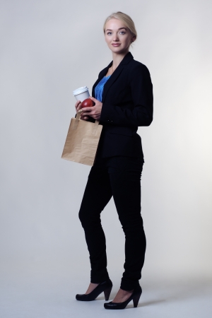 business woman holding a brown paper bag and a takeaway cup on her lunch breakの写真素材