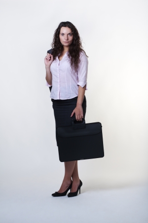 full length shot of standing woman holding a briefcase and a suit jacket over her shoulderの写真素材