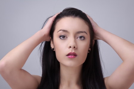 Pretty woman with long straight hair looking at camera running her hands through her hairの写真素材