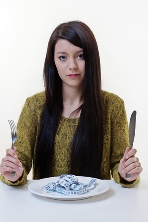 beautiful young woman keeping a diet and in shape, concept represented by showing a tape measure on her dinner plateの写真素材