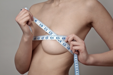 topless woman measuring her breastsの写真素材