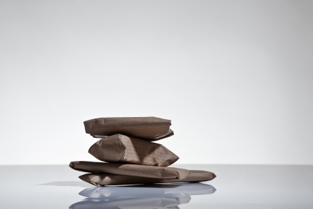 still life image of small parcels wrapped up in brown paper shot on a white background in the studioの写真素材