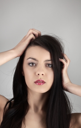 woman grabbing her hair in on grey studio backgroundの写真素材