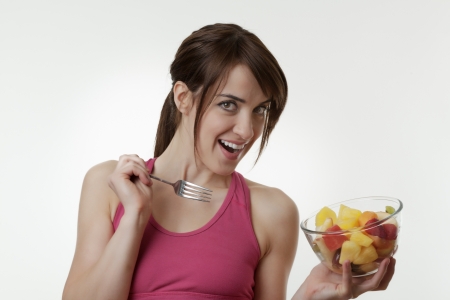 Woman holding a blow of fruit in her gym clothes shot in the studioの写真素材