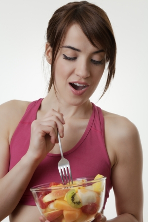 Woman holding a blow of fruit in her gym clothes shot in the studioの写真素材