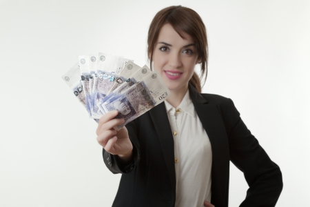 Portrait of happy business woman holding fanned english banknotes