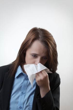 Businesswoman blowing her nose flu going around at workの写真素材