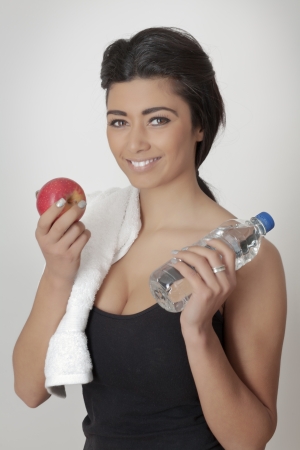young asian woman in fitness equipment with towel  holding an apple and bottled waterの写真素材