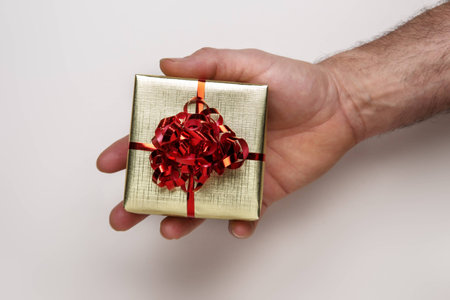 man's hand holding a small gift box with a ribbon around the box の写真素材