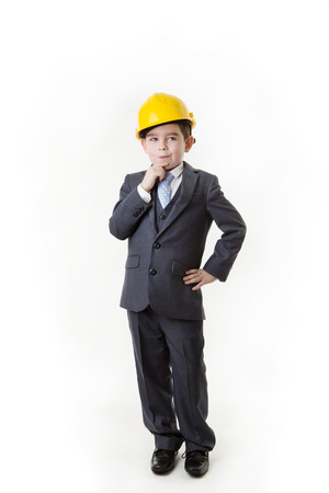 young boy pretending he's an architect wearing a hard hat thinking to himselfの写真素材