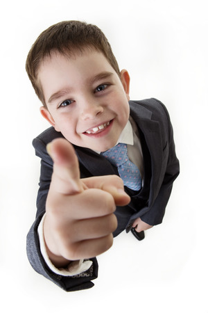 looking down at a happy small boy dressed up as a business person pointing his finger at youの写真素材